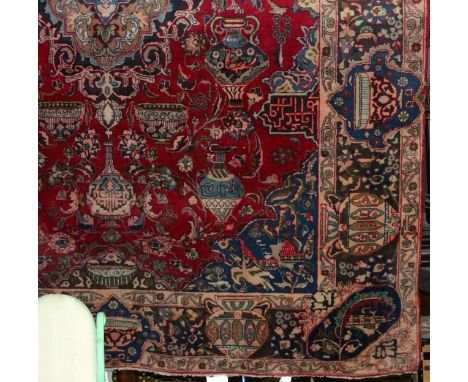 A large Persian style wool carpet the red field with abstract floral detail set within alternating running borders, 380cm x 2