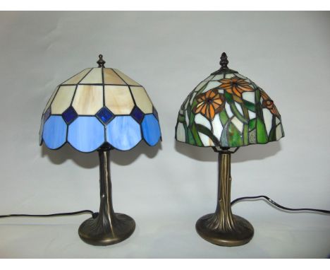 Two reproduction table lamps with leaded glass shades raised on simulated trunk like stems