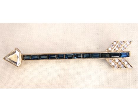 An Art Deco 14k gold sapphire and diamond arrow brooch with channel set sapphire shaft and free cut diamond, point and single