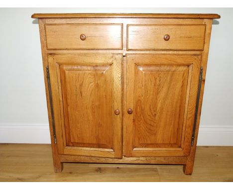 A Wesley Barrell rustic oak side cabinet in the French manner enclosed by two panelled doors and two frieze drawers with stee