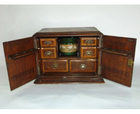 A Victorian smokers cabinet enclosed by two doors, the interior fitted with a ceramic jars and six further drawers