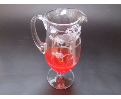 A 20th century studio glass ewer with a ruby tint to the lower section and with well etched decoration of an antelope, with i