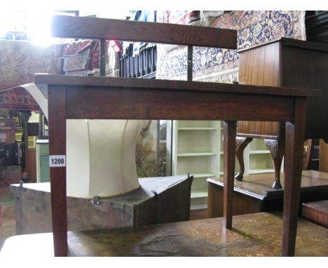 A vintage oak luggage stand of rectangular form with open slatted top and raised back rail, raised on four square tapered leg