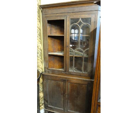 An early 19th century Welsh oak freestanding corner cupboard, the lower section enclosed by two panelled doors, the upper sec