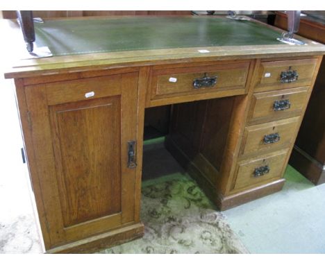 An Edwardian medium to light oak kneehole writing desk, the rectangular top with inset green leather writing surface over a p