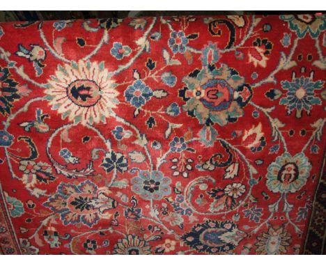 A substantial Persian wool red ground carpet with abstract floral decoration set within alternating red and white banded runn