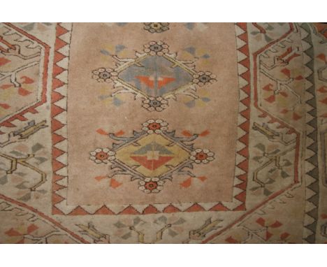 A Turkish wool carpet in pastel shades with geometric detail upon a pale fawn ground within alternating borders, 260cm x 170c