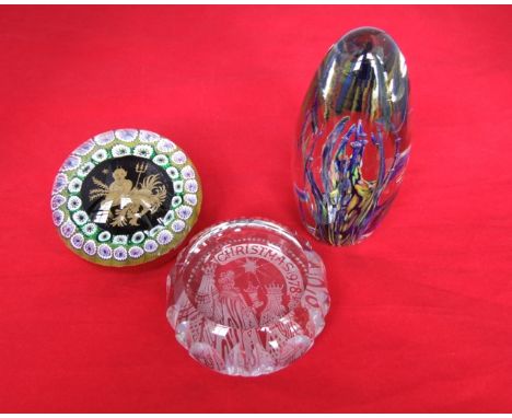 An unusual millefiori glass paper weight with double garland of floral canes surrounding a black ground panel with gilt decor