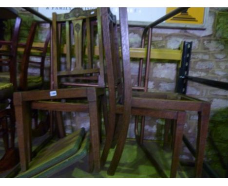 A set of four Art Nouveau oak stick back dining chairs with carved detail, drop in seats and raised on square taper supports