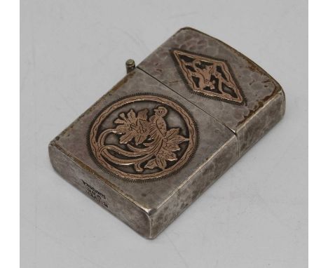 A 20th century textured white metal zippo type pocket cigarette lighter, having a yellow metal inlaid decoration in the form 