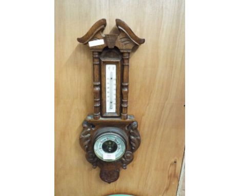 A carved oak barometer thermometer