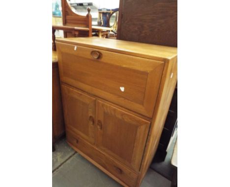 An Ercol cabinet having fall flap above a cupboard with drawer under