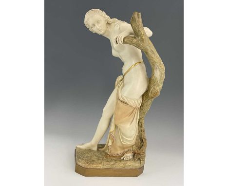 A Royal Worcester figure 'The Bather', circa 1903 modelled as a semi robed maiden afore a tree stump on naturalistic ground, 