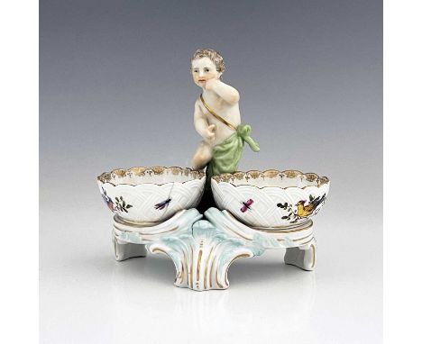 A Berlin porcelain figural double salt cellar, 19th century, the central putto between two basket moulded dishes painted with