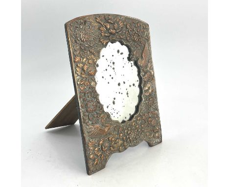 A Japanese embossed copper and silver plated easel mirror, cast in relief with chrysanthemums and dragons, bracket feet, 32.5
