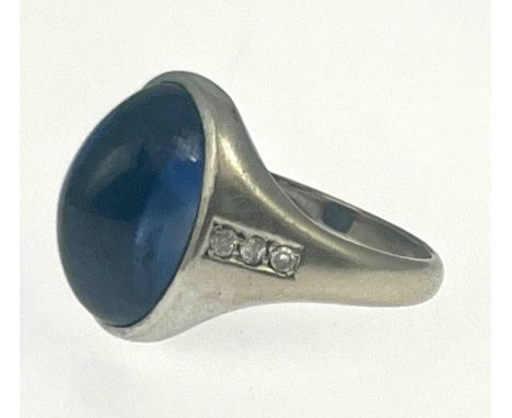 A synthetic sapphire cabochon band ring, white metal (probably platinum) with diamond line shoulders and central oval stone, 