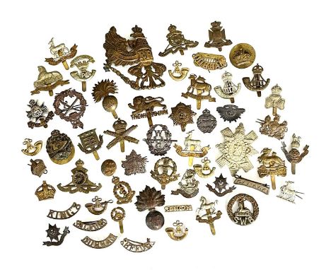 A collection of early 20th century British military cap badges and shoulder titles, including Machine Gun Corps, Middlesex Re