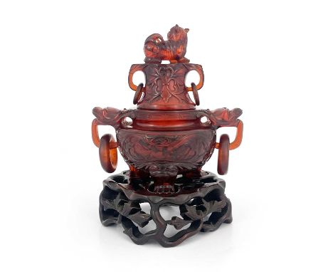 A Chinese pressed cherry amber censer, ring handles and lid, modelled in low relief with foliate scrolls, lion finial, 18cm h
