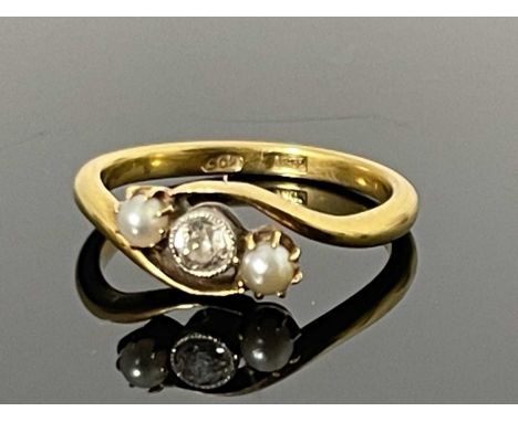 An 18ct gold diamond and pearl set three stone twist ring, the bezel set single diamond flanked by claw set pearls, ring size