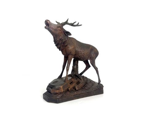 A Black Forest carved wooden model of a stag, standing on a rocky outcrop with head raised, five-point antlers, signed with l