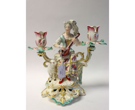 A Derby porcelain figural candelabrum, circa 1760-65, modelled as a shepherdess with lute and lamb, on Rococo scroll base, tw