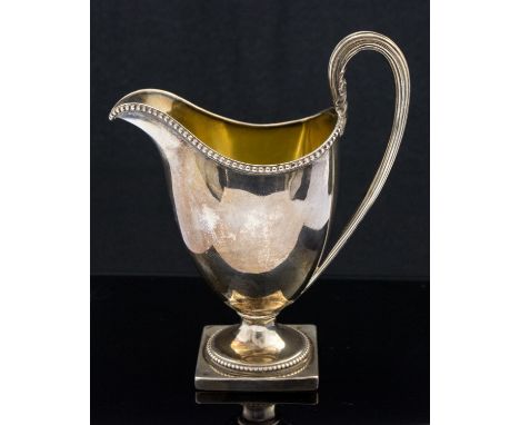 A George III silver cream jug, Neoclassical helmet form, reeded acanthus handle and beaded borders, on square base, gilt inte