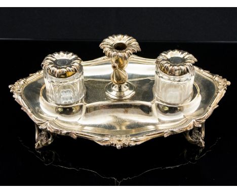 A Victorian silver ink stand, cast foliate and shell borders, on pierced bracket feet, two glass inkwells and a candlestick w