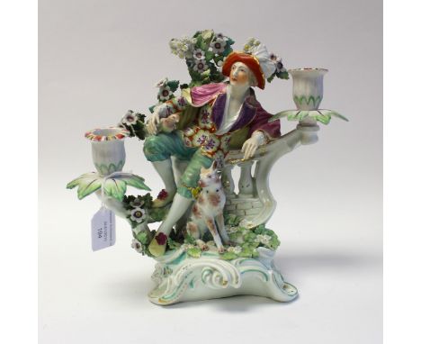 A Derby porcelain figural candelabrum, circa 1760-65, modelled as a man reclining on a balustrade, with dog and boccage, patc