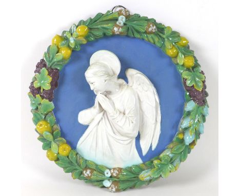 A Continental 'Della Robbia' faience and terracotta relief plaque, depicting an angel in prayer, within a cast border of moul