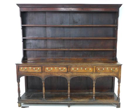 A large George III oak Welsh dresser, cornice over a closed three shelf waterfall plate rack, the base section with four frie