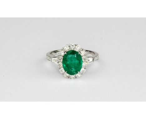 An 18ct white gold (stamped 750) ring set with an oval cut emerald surrounded by brilliant cut diamonds, approx. 2.19ct emera