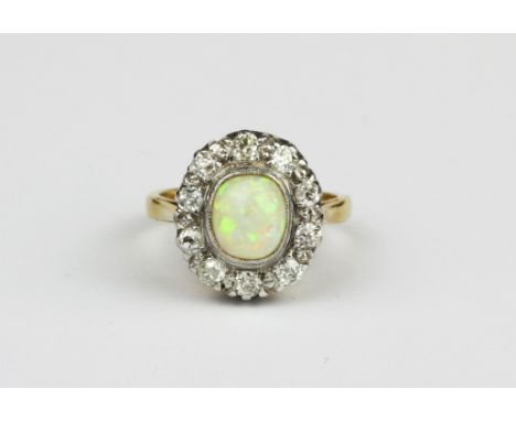 A yellow and white metal (tested minimum 9ct gold) cluster ring set with a cabochon cut opal surrounded by brilliant cut diam