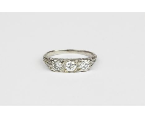 A white metal (tested high carat gold) trilogy ring set with three brilliant cut diamonds, (N).