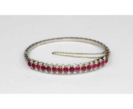 A French 18ct white gold (hallmarked with an owl) bangle set with rubies and diamonds, L. 6cm.