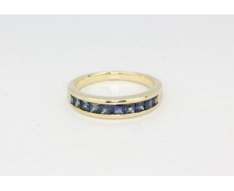 A 9ct yellow gold half eternity ring set with princess cut sapphires, approx. 3.6gr, (Q).
