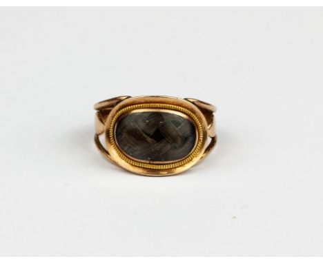 A gilt metal (tested minimum 9ct gold) mourning ring with an oval shaped hair compartment, (J).