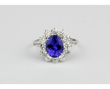 An 18ct white gold (stamped 750) cluster ring set with an oval cut tanzanite surrounded by brilliant cut diamonds, (N.5)