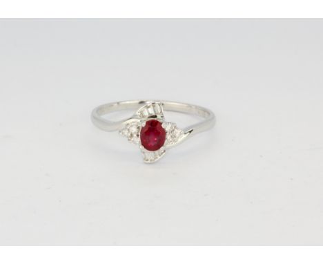 An 18ct white gold (stamped 750 and 18k) ring set with an oval cut natural unheated ruby and brilliant and baguette cut diamo