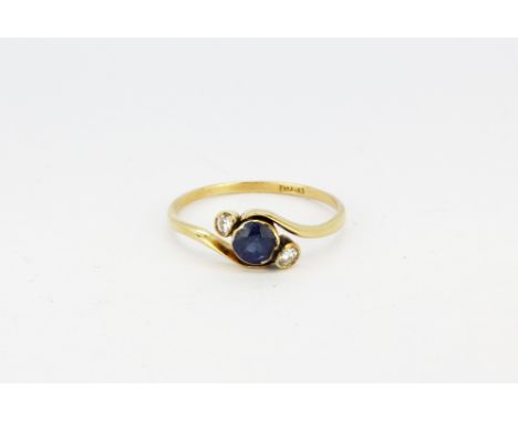 An antique 18ct yellow gold (stamped 18ct) crossover ring set with a round cut sapphire and two brilliant cut diamonds, (P).