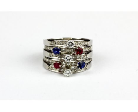 A white metal (tested 18ct gold) ring set with brilliant cut diamonds, rubies and sapphires, (O).
