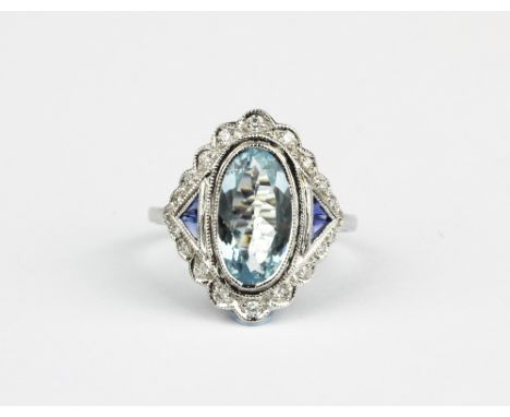 An 18ct white gold (stamped 18k) ring set with an oval cut aquamarine and sapphire and diamond set shoulders, (N.5).