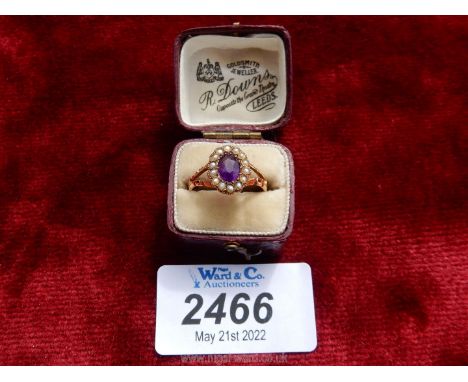 A maroon presentation cased 9 carat gold ladies ring set with a central oval Amethyst with a perimeter set with fourteen tiny