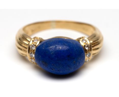 18 kt. Gouden ring, centraal bezet met een cabochon geslepen tonvormige lapis lazuli met aan weerszijde een band bezet met br