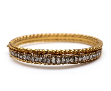 14 kt. Gouden stijve armband, 19e eeuw. Bestaande uit twee getwiste banen waartussen een rij roosgeslepen diamanten, in groot