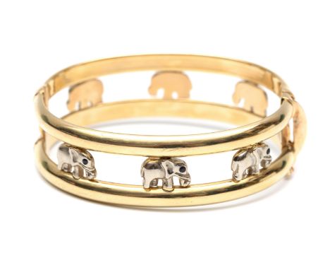 14 kt. Gouden stijve armband, bestaande uit twee banen waartussen witgouden olifanten met een oogje van saffier bruto 28,1 gr