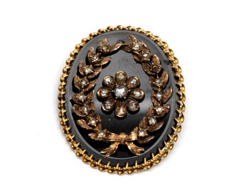 14 kt. Gouden ovale broche. Bezet met een licht concave onix, waarop bloem in een een lauwerkrans vormig applique, bezet met 