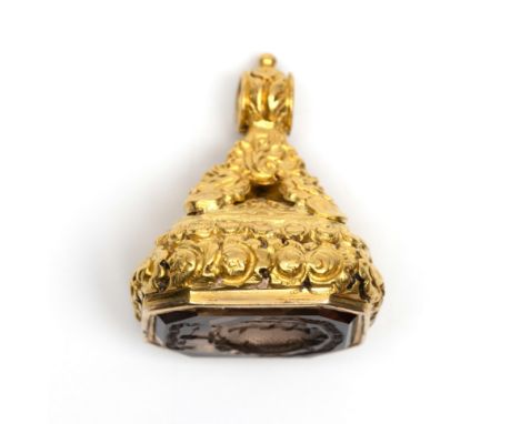 18 kt. Gouden cachet, 19e eeuw. Het geheel rijkelijk gedecoreerd met bloemen en bezet met een rookkwarts welke is gegraveerd 