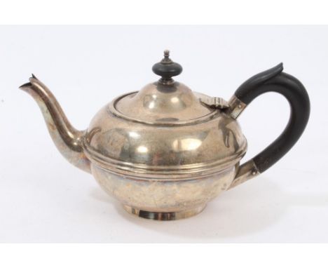 Early George V silver bachelors teapot of compressed form, with ebony loop handle and hinged domed cover with turned ebony fi