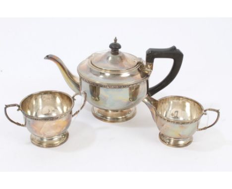 1930s three piece silver tea set - comprising teapot of cauldron form, with flower-head border, angular ebony handle and hing