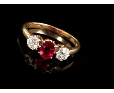 Ruby and diamond three stone ring with an oval mixed cut ruby flanked by two old cut diamonds, in claw setting, on gold shank